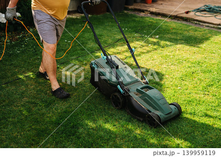 Person mowing lawn in backyard garden, home lawn care and summer yard maintenance 139959119