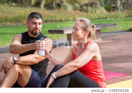 Two Friends Sharing Water During Outdoor Fitness Workout Two Friends Sharing Water During Outdoor Fitness Workout 139959190