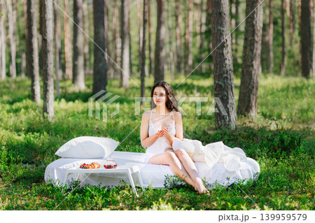 Young woman has breakfast in bed in a summer forest Young woman has breakfast in bed in a summer forest 139959579