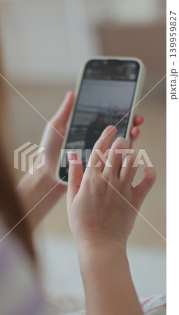 Vertical video. Little girl watching news feed social media smartphone message sitting cozy couch. Digital lifestyle. 139959827