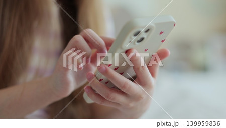 Close up little child girl using mobile phone at home. Daughter scrolling smartphone technology watching funny video in social media. The problem of addiction to gadgets. 139959836