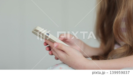Close up little child girl using mobile phone at home. Daughter scrolling smartphone technology watching funny video in social media. The problem of addiction to gadgets. 139959837