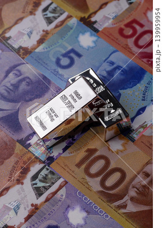 A silver bar, white metal against a backdrop of Canadian money, as a concept. A silver bar A silver bar, white metal against a backdrop of Canadian money, as a concept. A silver bar 139959954
