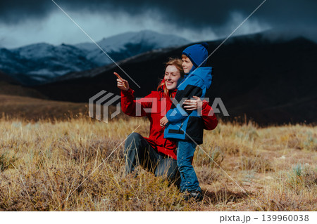 Mother and son looking out into the mountains in dark stormy weather Mother and son looking out into the mountains in dark stormy weather 139960038