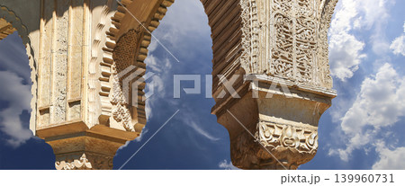 Arches in Islamic (Moorish) style (against the background of a beautiful sky with clouds) in Alhambra, Granada, Spain Arches in Islamic (Moorish) style (against the background of a beautiful sky with clouds) in Alhambra, Granada, Spain 139960731