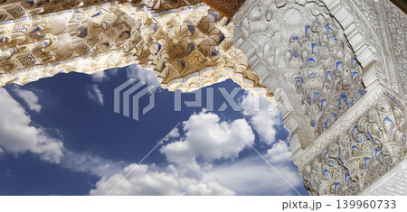 Arches in Islamic (Moorish) style (against the background of a beautiful sky with clouds) in Alhambra, Granada, Spain Arches in Islamic (Moorish) style (against the background of a beautiful sky with clouds) in Alhambra, Granada, Spain 139960733