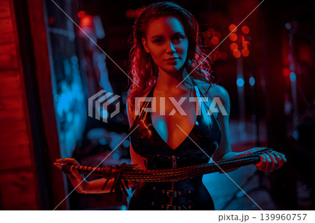 Young bdsm style woman with whip portrait in black latex suit 139960757