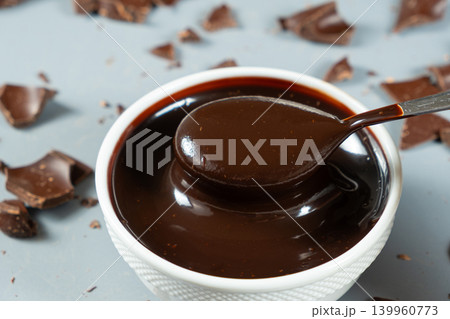 Smooth melting chocolate sauce flowing from a spoon Smooth melting chocolate sauce flowing from a spoon 139960773