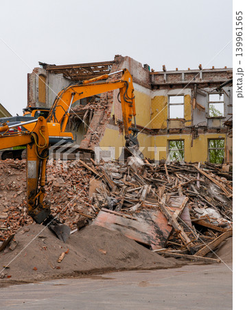 Excavator demolishing abandoned brick building with rubble and timber debris at construction site Excavator demolishing abandoned brick building with rubble and timber debris at construction site 139961565