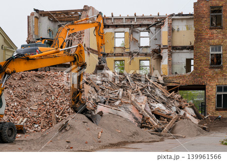 Heavy excavators demolishing old brick building with rubble and timber debris at urban site Heavy excavators demolishing old brick building with rubble and timber debris at urban site 139961566