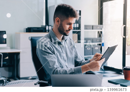Tired worker. A tired businessman works in the evening. A man in office clothes is holding his temples. Problems in business. The businessman is trying to solve the problems that have arisen. 139961673