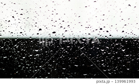 Raindrops on glass surface with sharp contrast background. Abstract water drops on a window during a rainstorm, divided by black and white background 139961993
