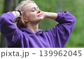 Blonde in purple sweatshirt doing morning exercises, breathing fresh air in forest 139962045