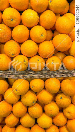 Abundance of fresh ripe oranges arranged in wicker shelves at a supermarket grocery display Abundance of fresh ripe oranges arranged in wicker shelves at a supermarket grocery display 139962544