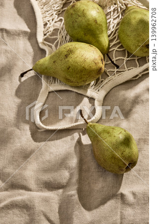 Fresh Italian pears in an Eco-Friendly Mesh Bag on a Linen Tablecloth. Top View Fresh Italian pears in an Eco-Friendly Mesh Bag on a Linen Tablecloth. Top View 139962708