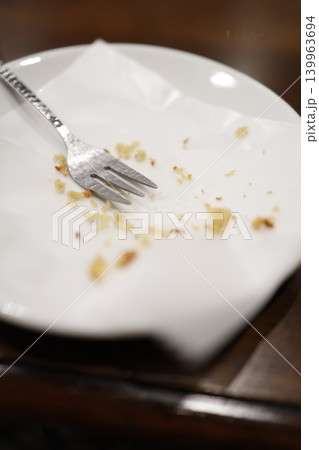 フォークと食べかす。白い皿の上のおやつの食べ残し。 フォークと食べかす。白い皿の上のおやつの食べ残し。 139963694