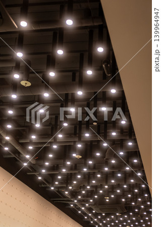 Modern ceiling design featuring integrated lights on exposed black tubes in a contemporary interior space. Modern ceiling design featuring integrated lights on exposed black tubes in a contemporary interior space. 139964947