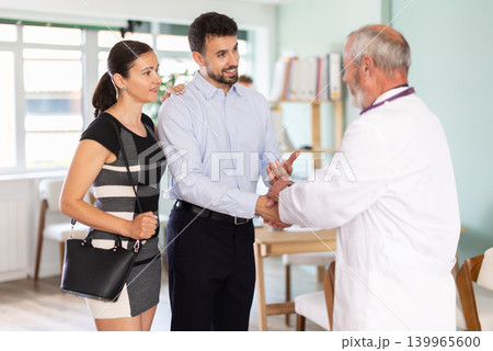 Family medical appointment. Senior male doctor and spouses, mens handshake Family medical appointment. Senior male doctor and spouses, mens handshake 139965600