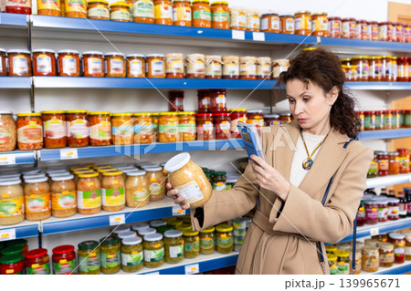 Female shopper scans barcode on jar of sauerkraut using a smartphone while shopping in grocery store Female shopper scans barcode on jar of sauerkraut using a smartphone while shopping in grocery store 139965671
