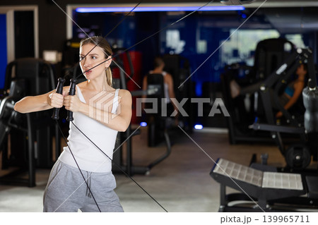 Active athlete young woman during exercises on crossover exercise machine with loops and weighting Active athlete young woman during exercises on crossover exercise machine with loops and weighting 139965711