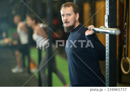 Determined young guy working out with weight rod during crossfit workout 139965737