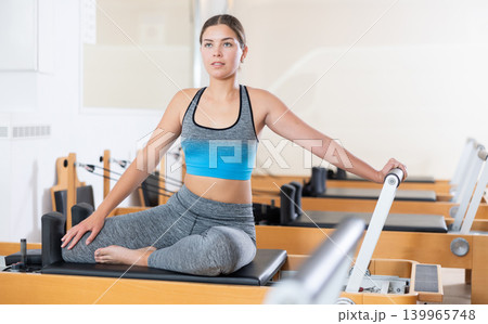 Young girl performing pilates exercises on reformer in studio Young girl performing pilates exercises on reformer in studio 139965748