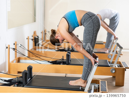 Girl practicing exercises on Pilates reformer during rehabilitation session Girl practicing exercises on Pilates reformer during rehabilitation session 139965750