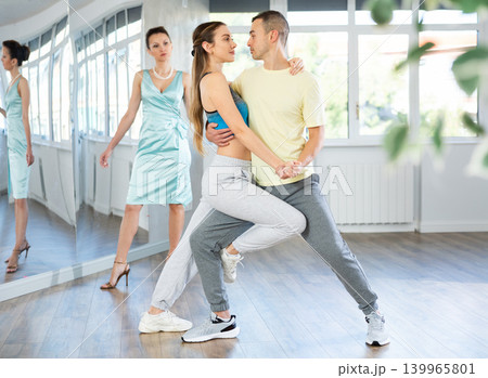 Couple in comfortable sports clothes learns tango dancing during individual lesson 139965801