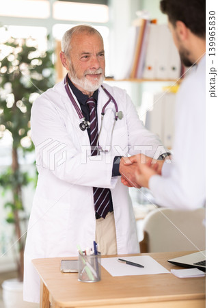 Successful medical appointment, senior male doctor and man patient shake hands. Successful medical appointment, senior male doctor and man patient shake hands. 139965830