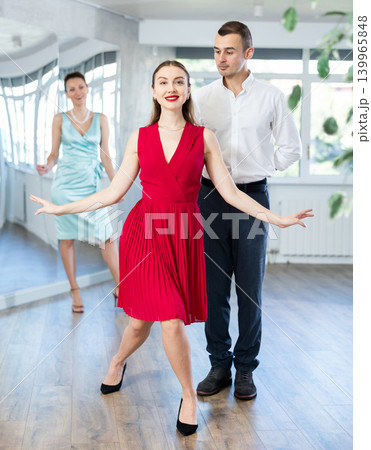 Couple in stage costumes learns waltz dancing during individual lesson Couple in stage costumes learns waltz dancing during individual lesson 139965848