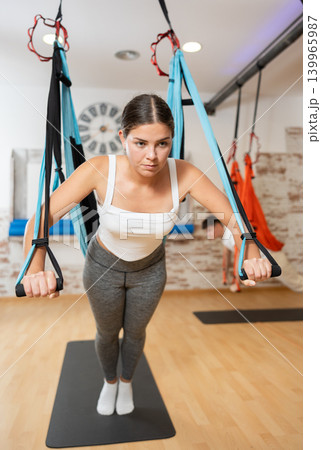 Sporty girl doing push-ups using TRX suspension straps during Pilates workout Sporty girl doing push-ups using TRX suspension straps during Pilates workout 139965987