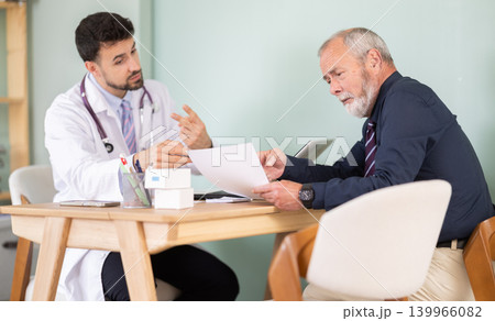 Adult doctor discussing medical tests with elderly male patient Adult doctor discussing medical tests with elderly male patient 139966082
