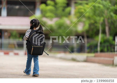 Back view of little child girl with a backpack walking into the school building. New semester concept 139966858