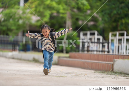 Excited little student with backpack running happily and raising her arms celebrating the end of school day 139966868
