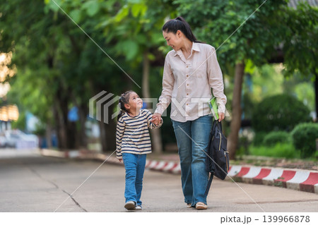 mother holding daughter's hand and walking together to school. First day of education. mother holding daughter's hand and walking together to school. First day of education. 139966878