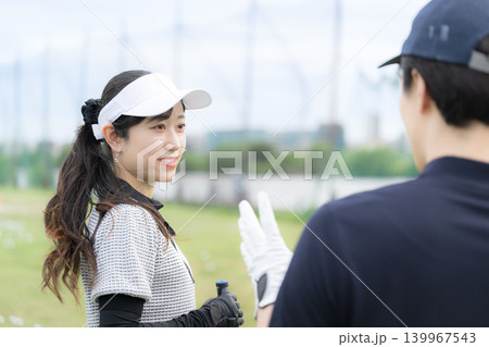 笑顔でゴルフを習う女性　ゴルフの先生と会話や2人でコミュニケーションをゴルフレッスンの様子 139967543