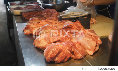 Various freshly chopped meat pieces spread across a market counter surface at an indoor Thai market stall. Butcher market concept Various freshly chopped meat pieces spread across a market counter surface at an indoor Thai market stall. Butcher market concept 139968569
