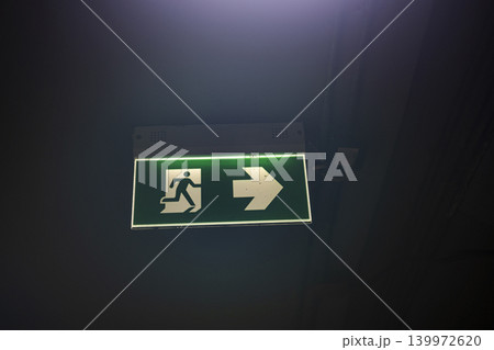 Green Fire Exit Sign For Emergency Light, A photo of green fire exit sign for emergency light, sign with running figure and arrow, perfect for safety campaign or emergency documentary. Green Fire Exit Sign For Emergency Light, A photo of green fire exit sign for emergency light, sign with running figure and arrow, perfect for safety campaign or emergency documentary. 139972620