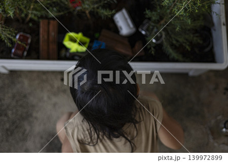 Toddler Playing Toy Car On Soil In Plant Pot, A warm documentary of toddler pushing toy car, focused face and tiny wheels leaving tracks in dirt, for everyday exploration or innocent discovery. 139972899