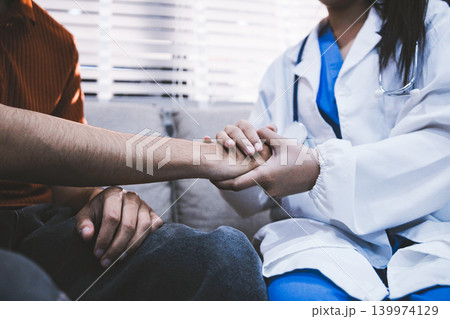 A doctor is holding hands with an elderly patient. 139974129