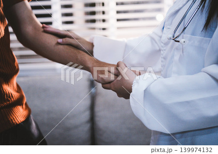 A doctor is holding hands with an elderly patient. 139974132