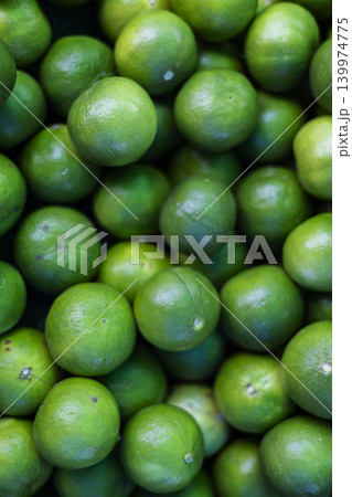 Fresh Harvested Green Limes For Sale At A Farmer Market. Close up of ripe citrus fruits with textured skin on local grocery stall, ideal for refreshing beverages or healthy cooking themes. 139974775