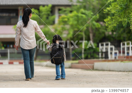 mother holding her daughter's hand and walking together to school. First day of education. 139974857