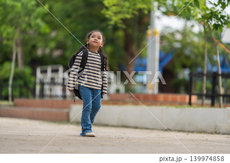 Brave little girl with backpack walking happily into school courtyard. Back to school concept 139974858