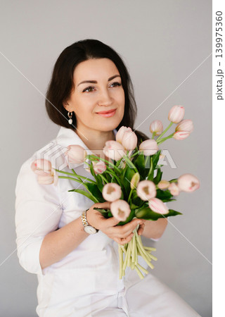 Dreamy Young Female Doctor Holding Fresh Tulips 139975360