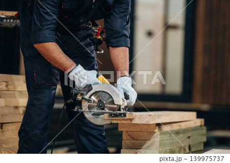 Cutting the wood. Close-up of a carpenter working by using professional tools in a workshop Cutting the wood. Close-up of a carpenter working by using professional tools in a workshop 139975737