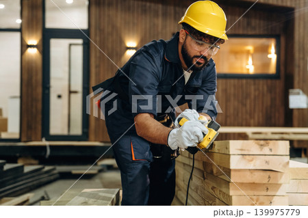Engaged in grinding. Male carpenter working with wooden materials in a professional workshop Engaged in grinding. Male carpenter working with wooden materials in a professional workshop 139975779