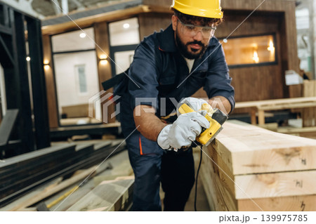 Man is focused, daily job. Male carpenter working with wooden materials in a professional workshop Man is focused, daily job. Male carpenter working with wooden materials in a professional workshop 139975785