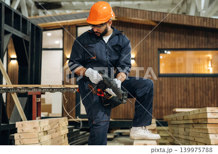 Tool for cutting in hands. Male carpenter working with wooden materials in a professional workshop 139975788