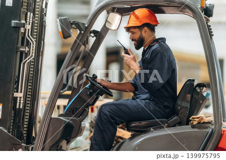 Ready to load. Warehouse worker operating a forklift while handling wooden materials 139975795